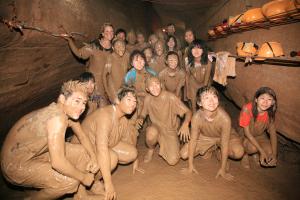 Caving in the mud in China, Guangxi province, a group photo of happy people in the mud